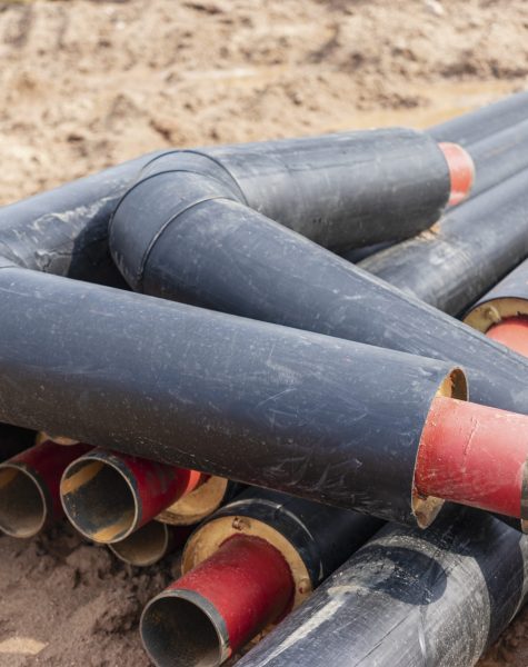 Laying heating pipes in a trench at construction site. Energy efficient insulated pipes. Cold and hot water, heating and heating system of apartments in the house