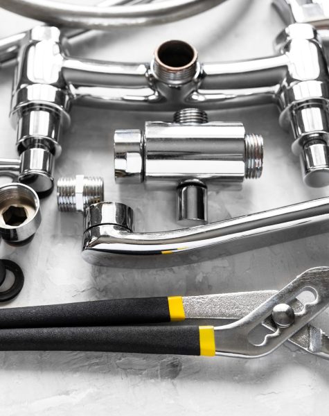 plumbing still-life with wrench, disassembled spout, shower faucet valve, diverter, gaskets on concrete board