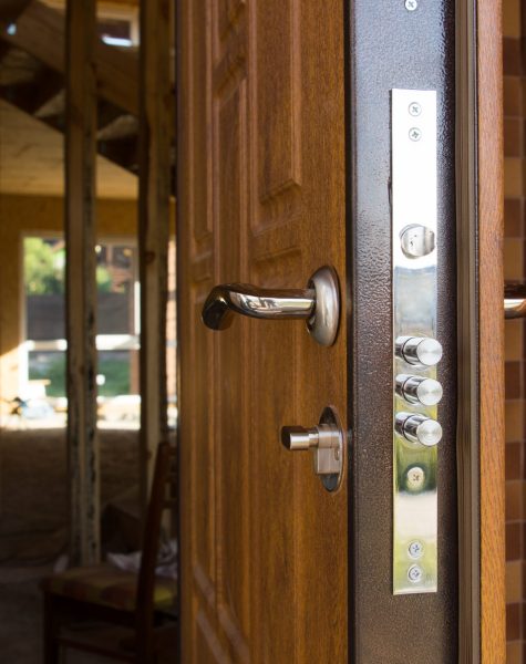 Safety lock on a new wooden front door showing the three security cylinders required by insurance companies for best premium quotations